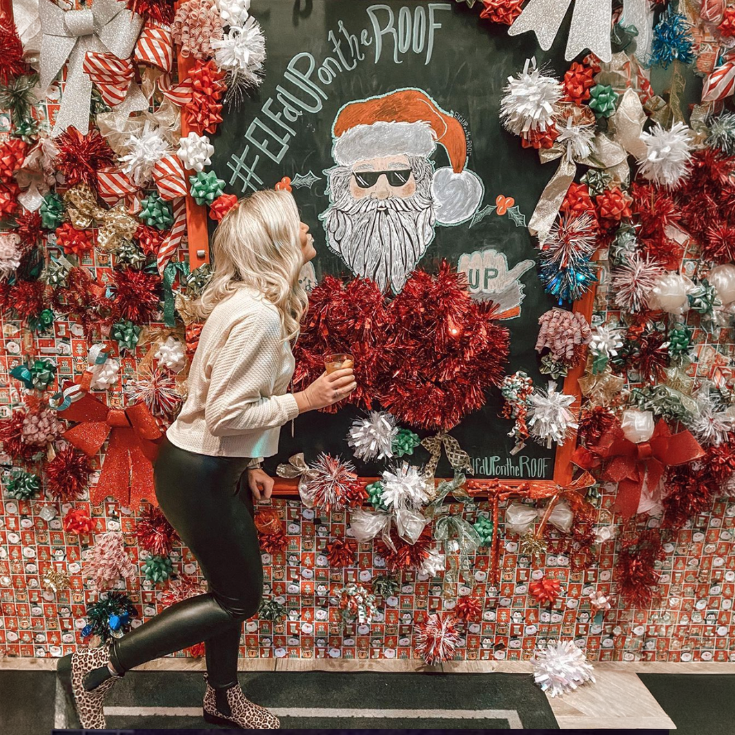 A lady kissing the Santa wall at Elf'd UP