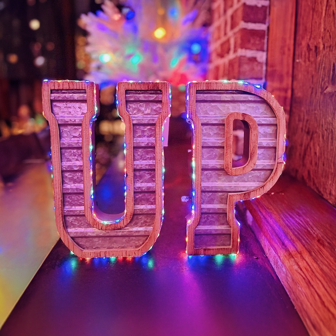 UP signage in front of festive lighting and decor